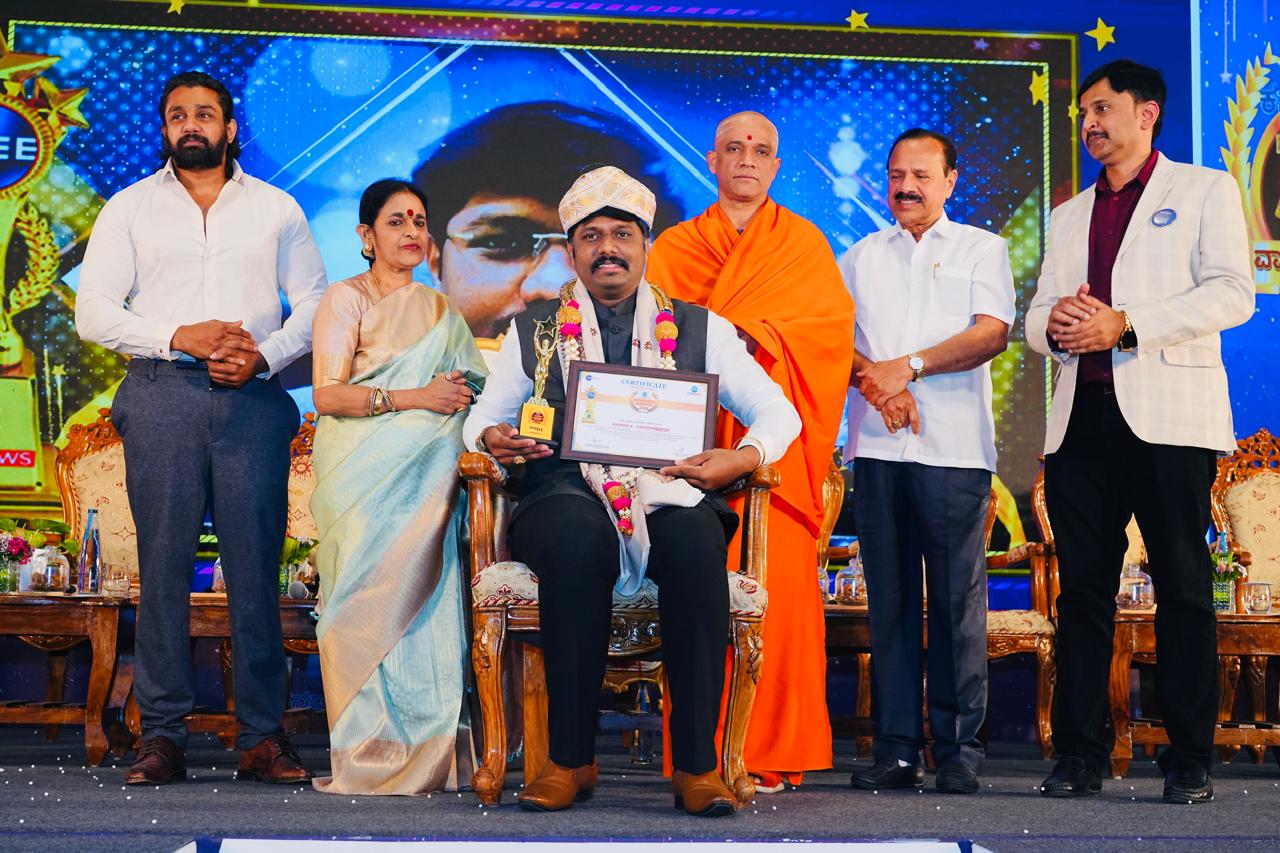 Naveen Krishnegowda receiving an award on stage with dignitaries