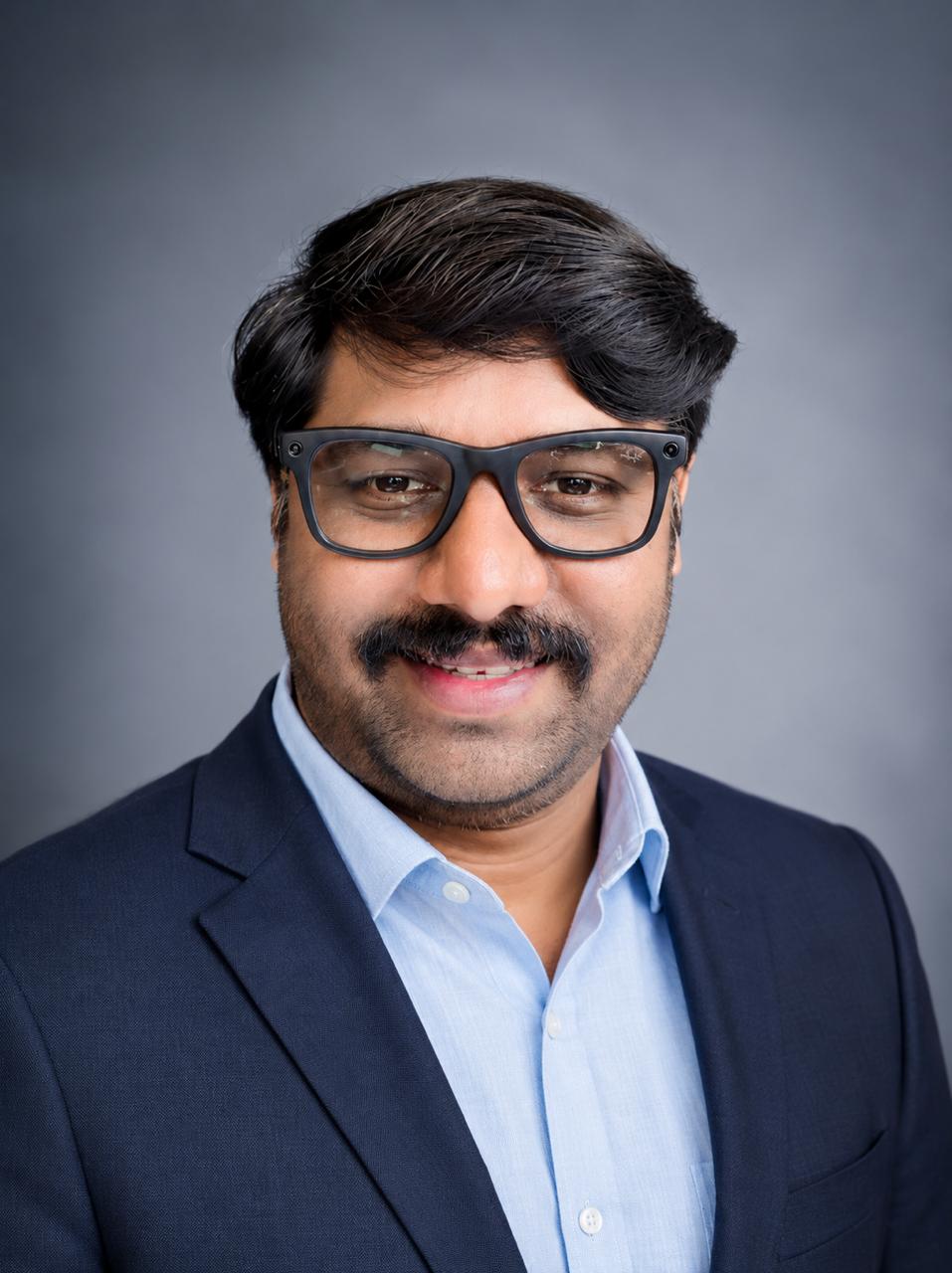 Naveen Krishnegowda in a dark navy suit